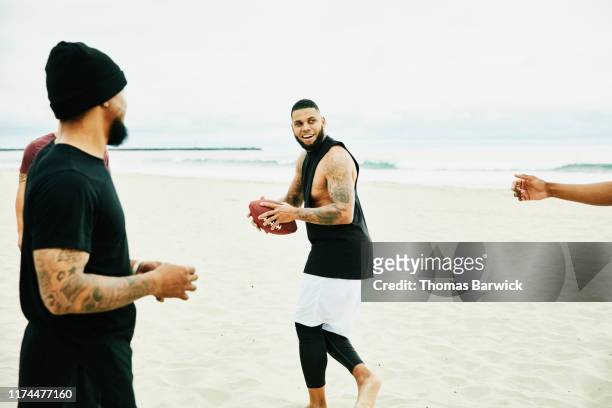 smiling man playing football on beach with friends - hunky guy on beach stock pictures, royalty-free photos & images