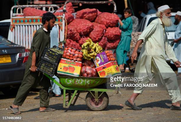 Labourer pushes a fruit laden trolley from a vegetable and fruit market in Islamabad on October 8, 2019.