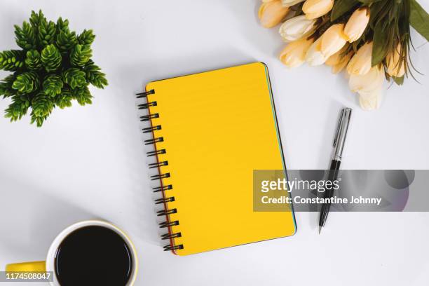 yellow notebook and coffee mug on work desk - white flower paper stock-fotos und bilder