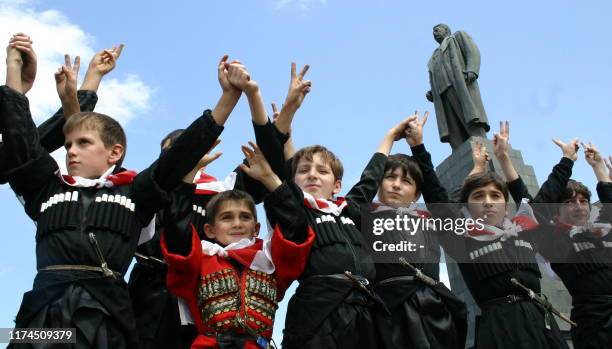 Georgian boys wearing traditional costumes raise their hands near a monument to Josef Stalin during a protest rally in Gori on September 1, 2008....