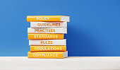 Books of Compliance And Regulations In Front Grey Wall