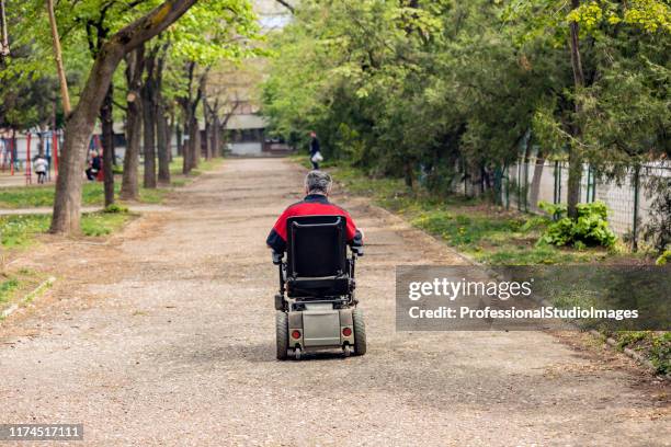 hombre discapacitado en silla de ruedas eléctrica en movimiento - mobility scooter fotografías e imágenes de stock