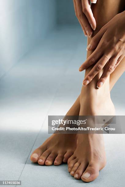 woman's hand touching her bare feet - womans bare feet fotografías e imágenes de stock