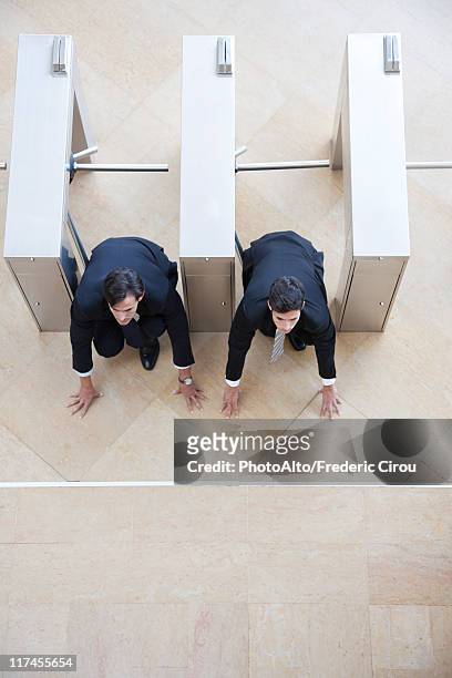 businessmen crouching in starting position in lobby turnstiles - hombre agachado fotografías e imágenes de stock
