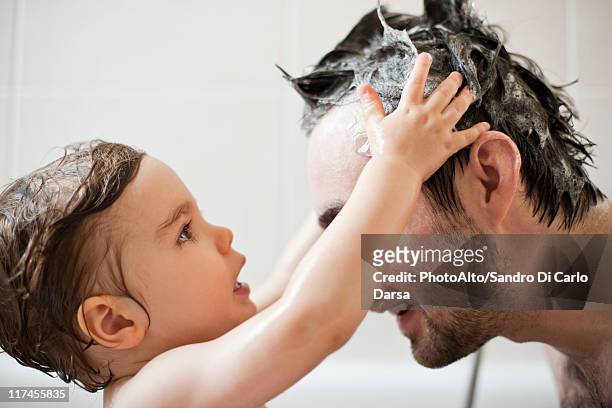 toddler boy washing father's hair in bath - bad body language stockfoto's en -beelden