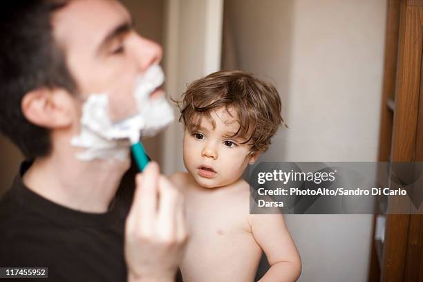 toddler boy watching his father shave - sandro rasa foto e immagini stock