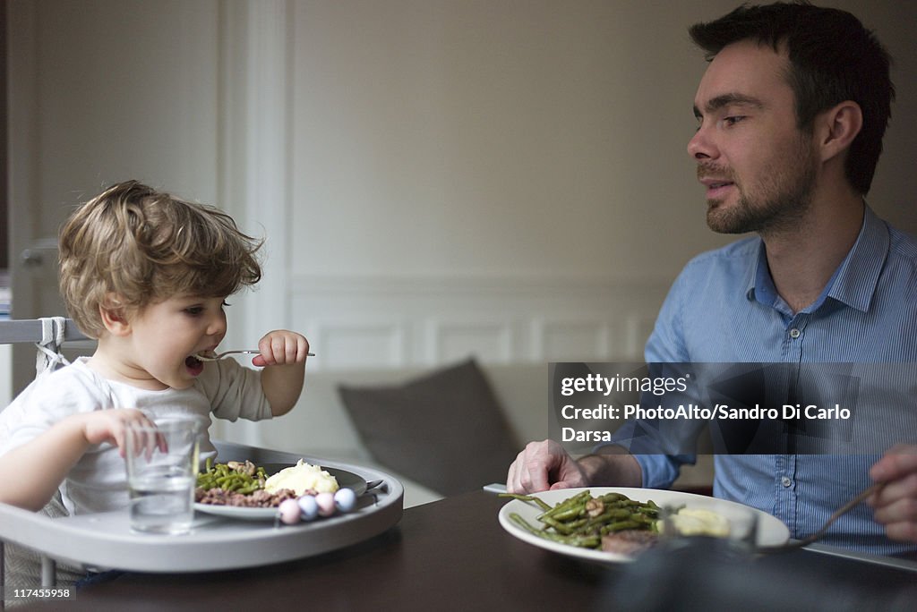 Father and toddler son eating dinner together