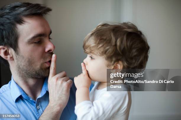 father teaching toddler son to hush - quiet gesture stock pictures, royalty-free photos & images