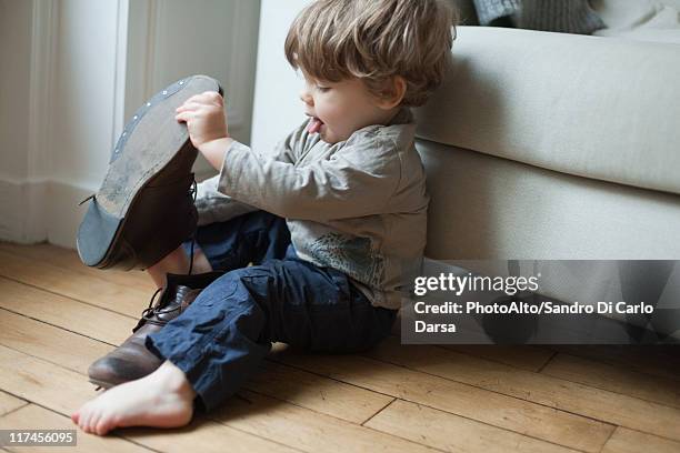 toddler boy playing with parent's shoes - passt nicht stock-fotos und bilder