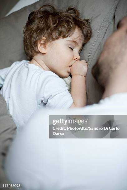 toddler boy sleeping beside father, cropped - thumb sucking stock pictures, royalty-free photos & images