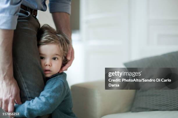 toddler boy holding on to father's legs - tímido imagens e fotografias de stock