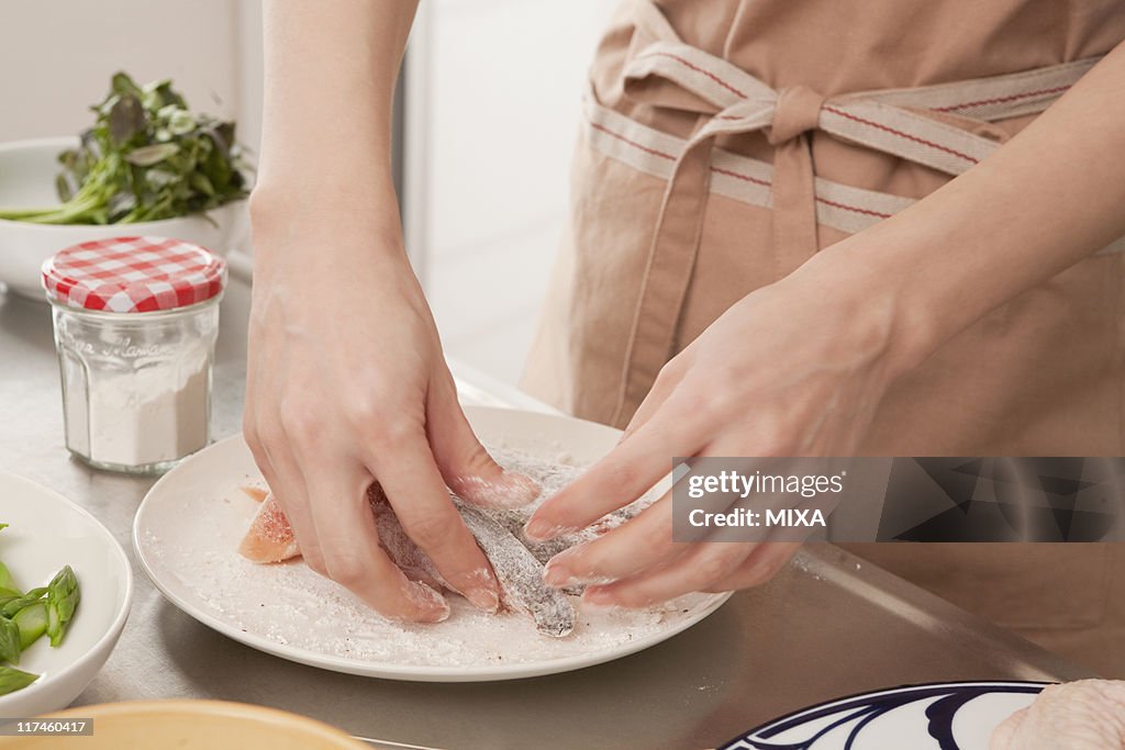 Woman coating salmon with flour
