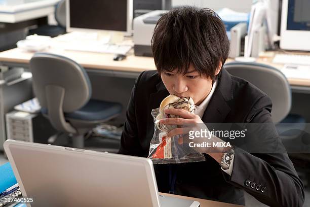 young businessman having meal at desk - ビジネス　食事 ストックフォトと画像