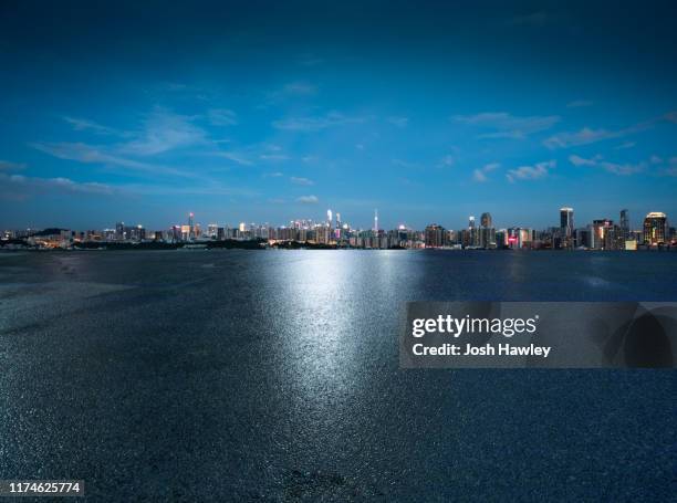 empty parking lot with cityscape background - wet asphalt stock pictures, royalty-free photos & images