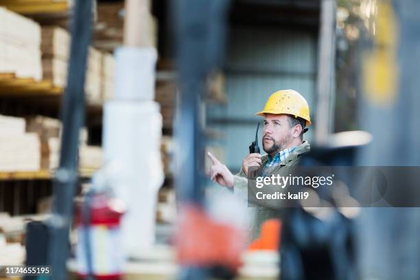 hispanic man on walkie talkie, working in lumber yard - walkie talkie stock pictures, royalty-free photos & images