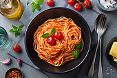 Pasta, spaghetti with tomato sauce in black bowl on grey stone background. Top view.