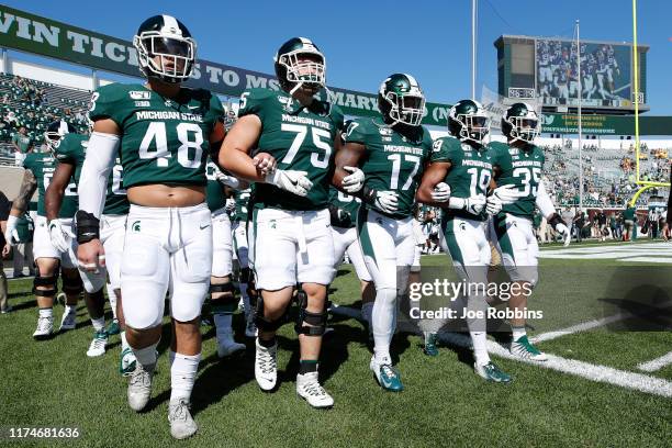 Michigan State Spartans players walk around the field with locked arms prior to the game against the Arizona State Sun Devils at Spartan Stadium on...