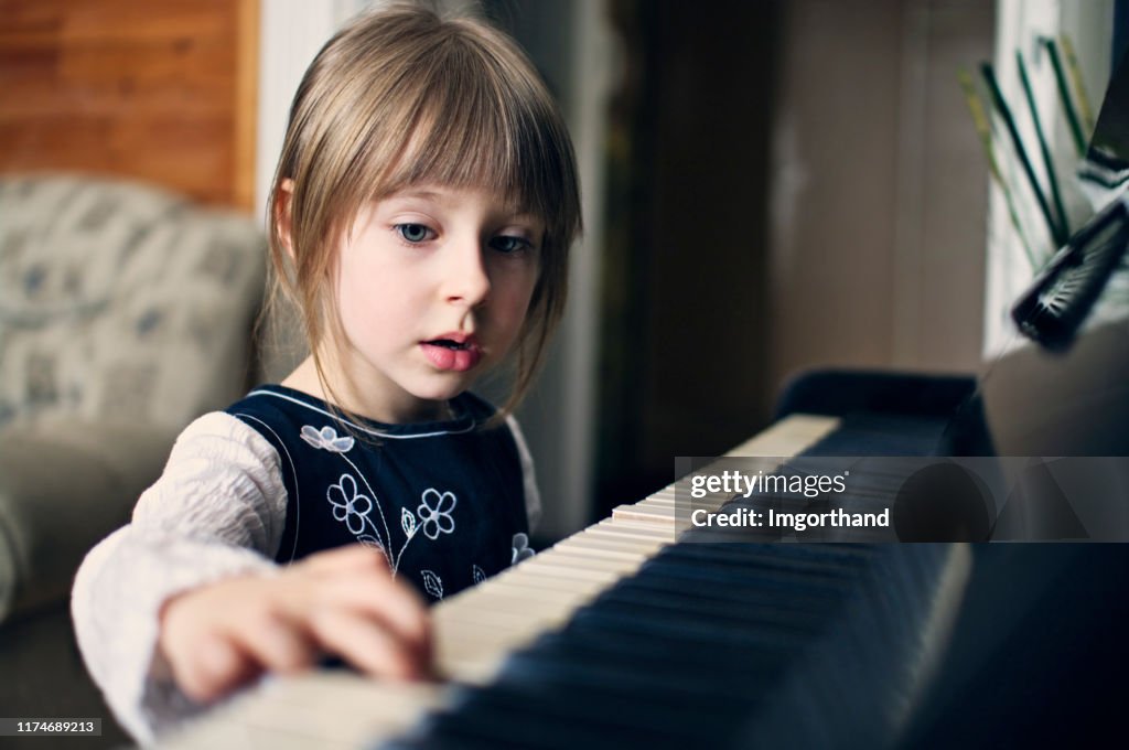 Four years old girl playing piano and singing