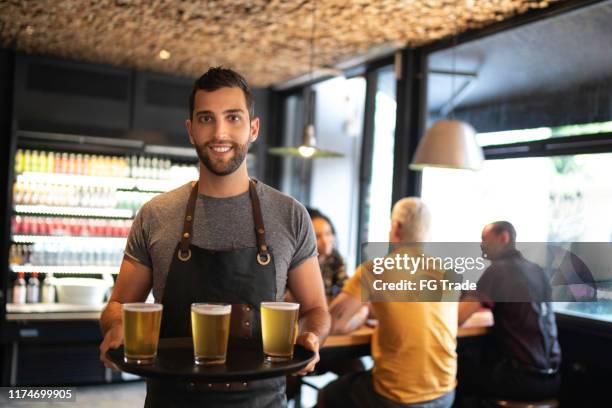 portrait of waiter serving beer - avental imagens e fotografias de stock