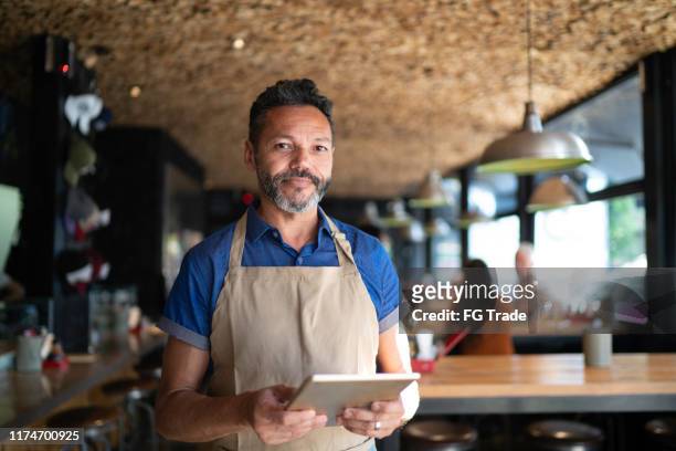 portrait of owner / waiter using digital tablet at restaurant - 50s bar stock pictures, royalty-free photos & images