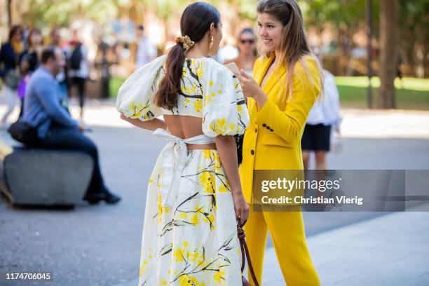 Bettina Looney is seen wearing yellow white dress with graphic print, brown bag and a guest wearing yellow suit outside Ports 1961 during London...