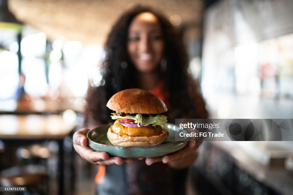 Waitress holding / showing a sandwich