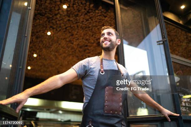 sonriente propietario de la tienda masculina mirando hacia otro lado en la puerta - brazil open fotografías e imágenes de stock