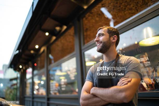 sonriente propietario de la tienda masculina mirando hacia otro lado en la puerta - brazil open fotografías e imágenes de stock