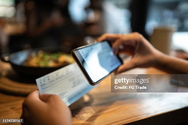 mann hinterlegt scheck per telefon im restaurant - strichkodeleser stock-fotos und bilder
