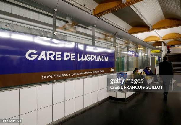 People walk next to a metro station sign especially designed to commemorate the 60th anniversary of France's famous comic characters Asterix and...