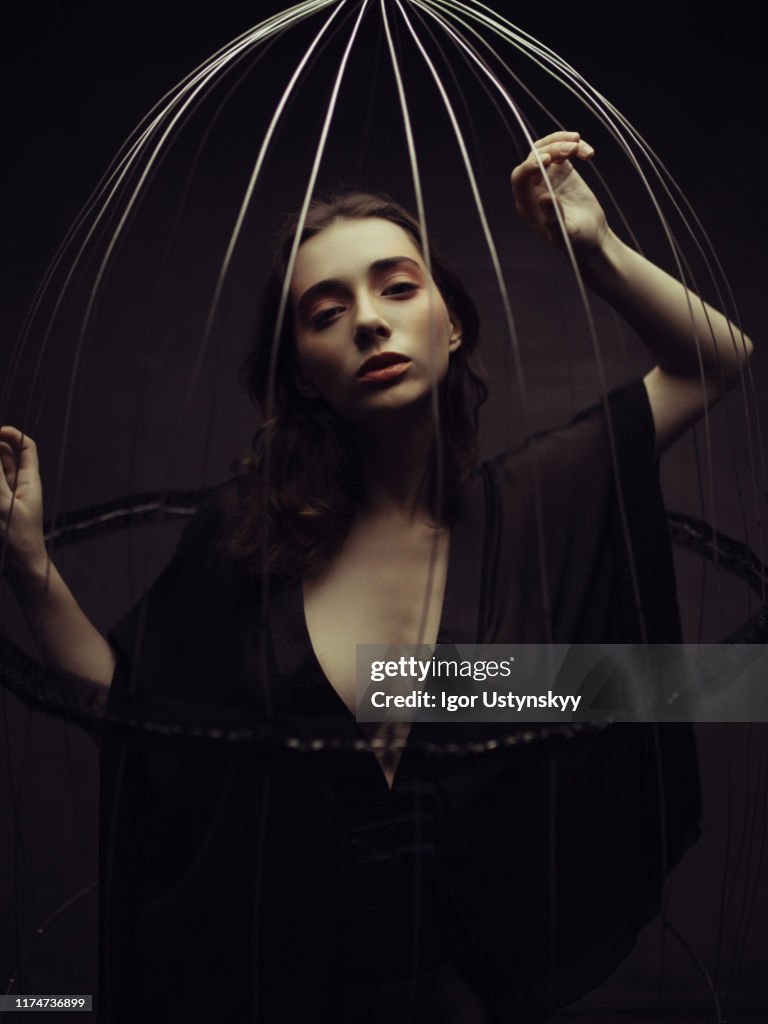 Young pensive woman trapped in birdcage