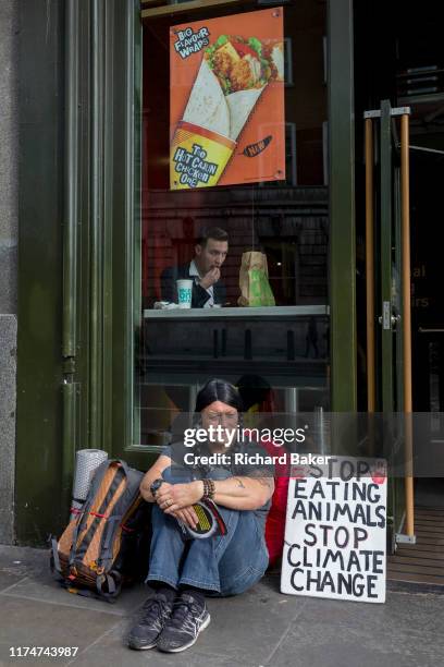 Food science protester sits outside a McDonalds restaurant in Whitehall during the environmental protest about Climate Change occupation of Trafalgar...