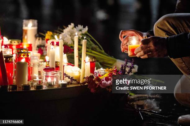 People leave candles and flowers at a vigil at the Marktplatz in Halle an der Saale, eastern Germany, on October 9 after a heavily-armed man shot two...