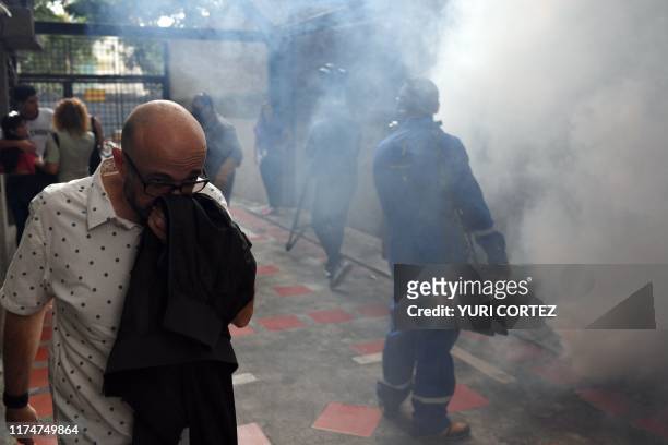 Man covers his nose as he walks past municipal workers fumigating against the aedes aegypti mosquito, vector of dengue fever, Zika fever and...