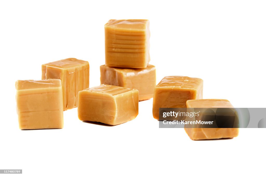 Unwrapped caramel candies on a white background