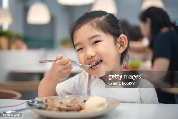 cute little girl eating - kid eating restaurant stock pictures, royalty-free photos & images