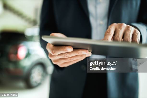 primer plano del vendedor de coches irreconocible utilizando una tableta digital. - salón de coches fotografías e imágenes de stock