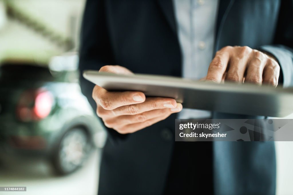 Close up of unrecognizable car salesman using digital tablet.
