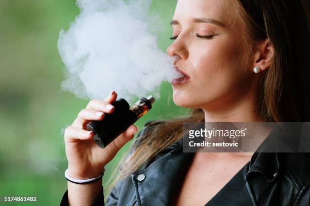 closeup of woman smoking electronic cigarette - electronic vapor stock pictures, royalty-free photos & images