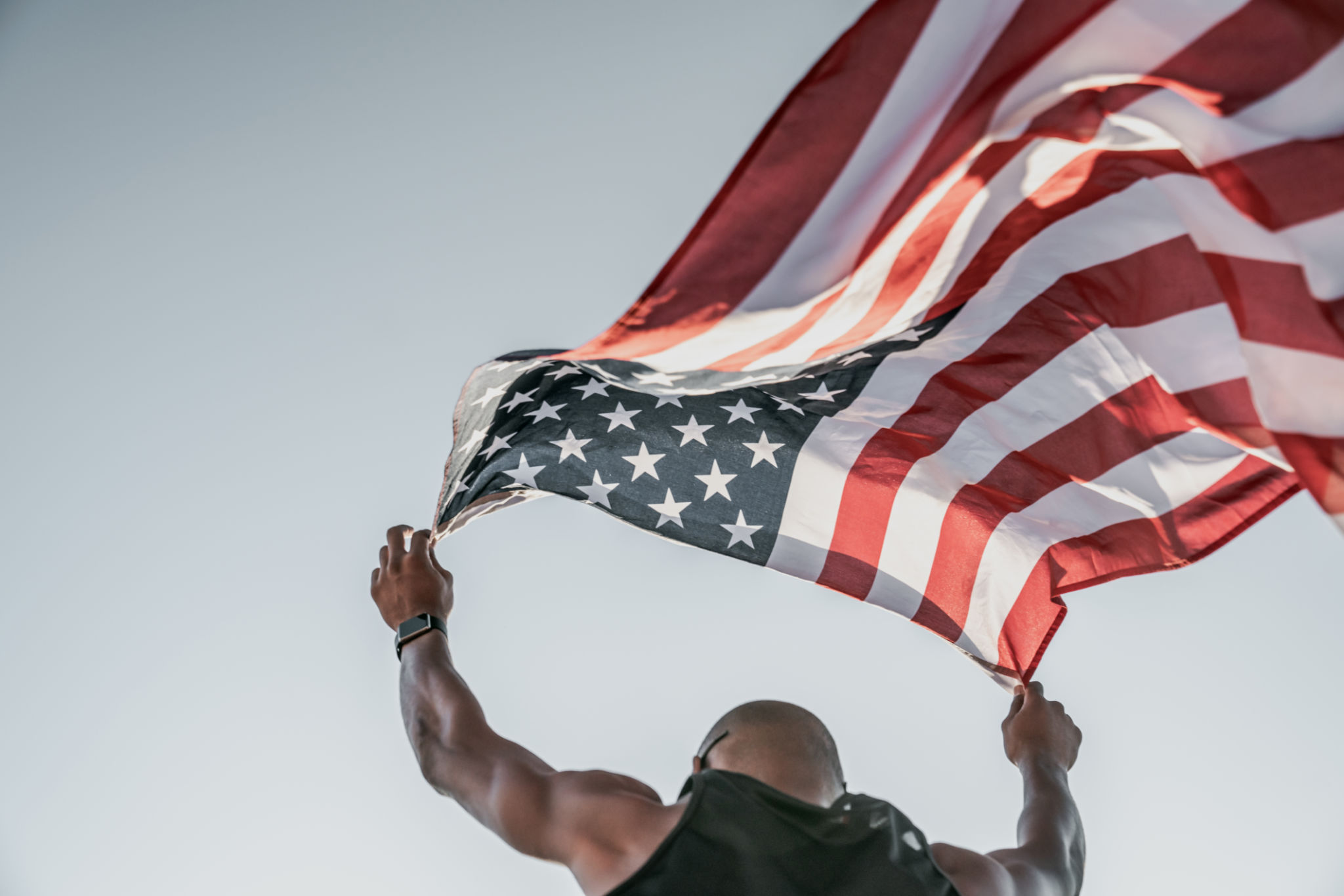 Low angle view of an athlete running on athletic track holding the american flag over the head Low angle view of an athlete running on athletic track holding the american flag over the head