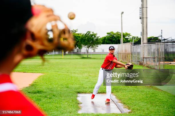 young hispanic baseball players warming up before game - baseball thrower stock pictures, royalty-free photos & images