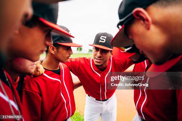 primer plano del equipo de béisbol acurrucado y escuchando al capitán - béisbol escolar fotografías e imágenes de stock