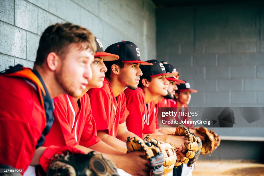 Baseball team members sitting in dugout focused on game