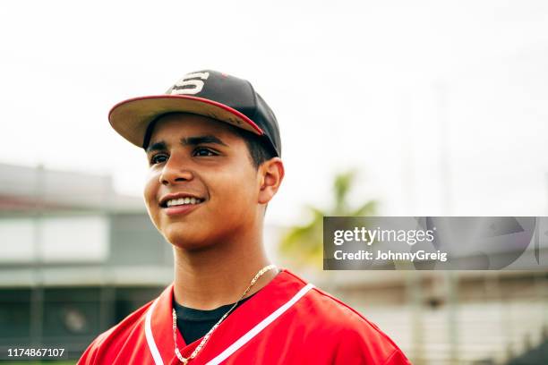 primer plano de un jugador de béisbol hispano sonriente mirando hacia otro lado - béisbol escolar fotografías e imágenes de stock