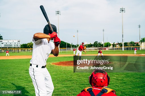 Rear view of baseball batter and catcher watching the pitch Rear view of baseball batter and catcher watching the pitch