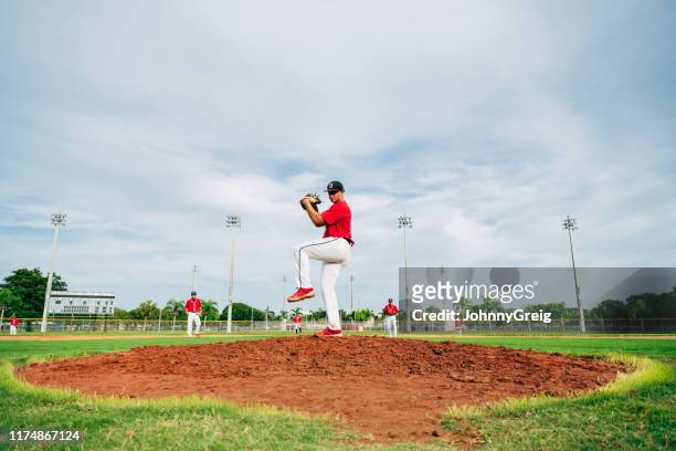 joven lanzador de béisbol hispano en posición de liquidación - béisbol escolar fotografías e imágenes de stock