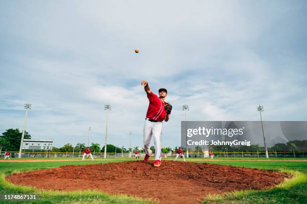 hispanic baseball player delivering a pitch from the mound - young baseball pitcher stock pictures, royalty-free photos & images