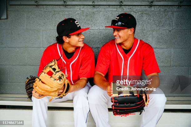 hispanic baseball players laughing side by side in dugout - dugout stock pictures, royalty-free photos & images