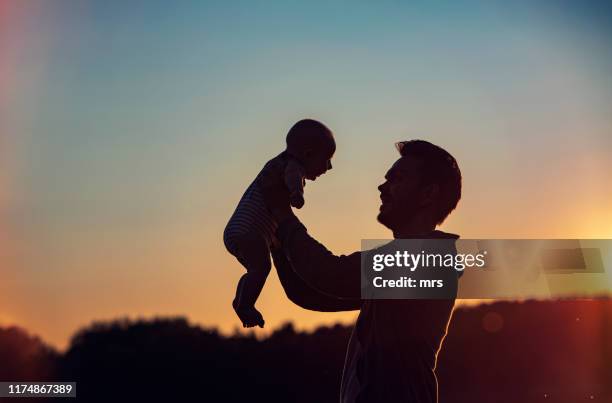 happy father lifting baby son - lifting kids silhouette stock pictures, royalty-free photos & images