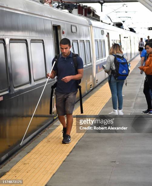 Young blind man prepares to board a Denver RTD Light Rail train at Union Station in Denver, Colorado.